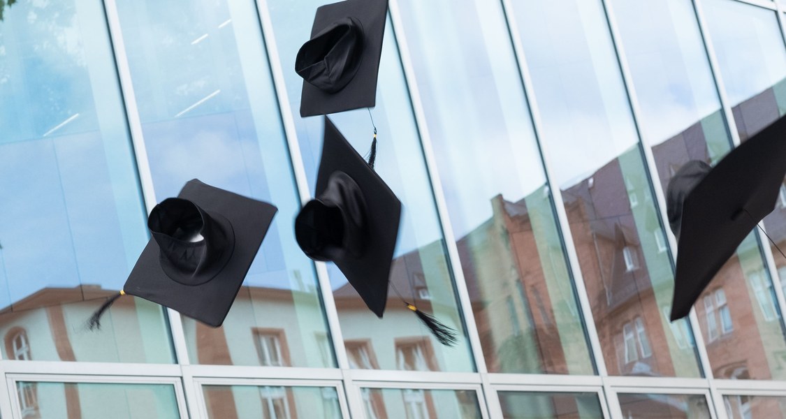 In die Luft geworfene Doktorhüte vor der UB