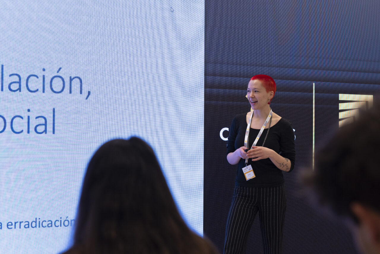 Ana Vucic presenting in front of a large screen displaying text.