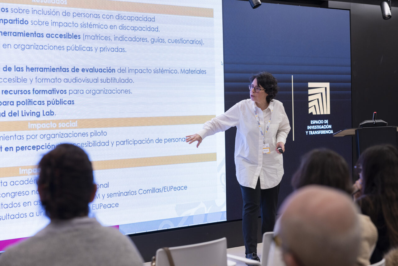 Barbara Calderón presenting in front of a large screen filled with text in Spanish, while audience members listen.