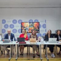 Professors and administrative staff of UNSA sitting at a table with laptops in front of them.