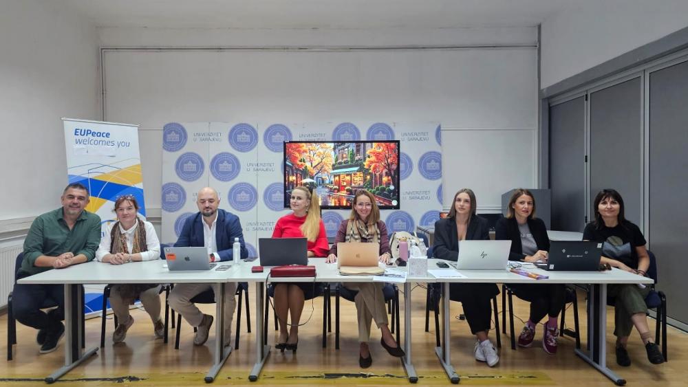 Professors and administrative staff of UNSA sitting at a table with laptops in front of them.