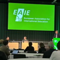 Three people on a podium at the EAIE 2025 conference. Left-to-right: Asli Ilgit (Cukurova University, Türkiye), Sebastian Kilde Westberg; University of Gothenburg & Markus Laitinen; University of Helsinki.