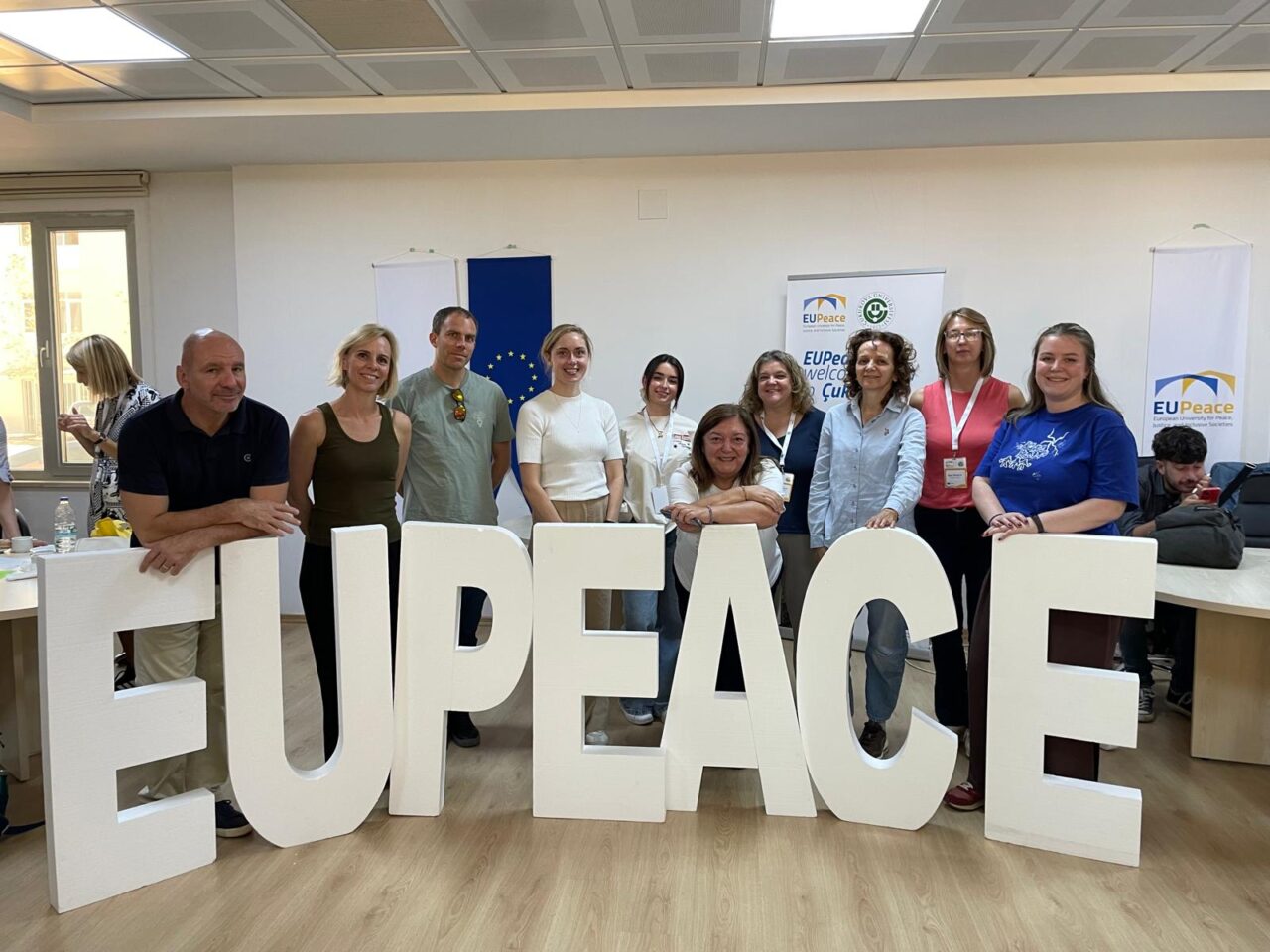 A group of people standing behind meter-high EUPeace letters.