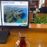 A glass with some brown in front of a computer screen.