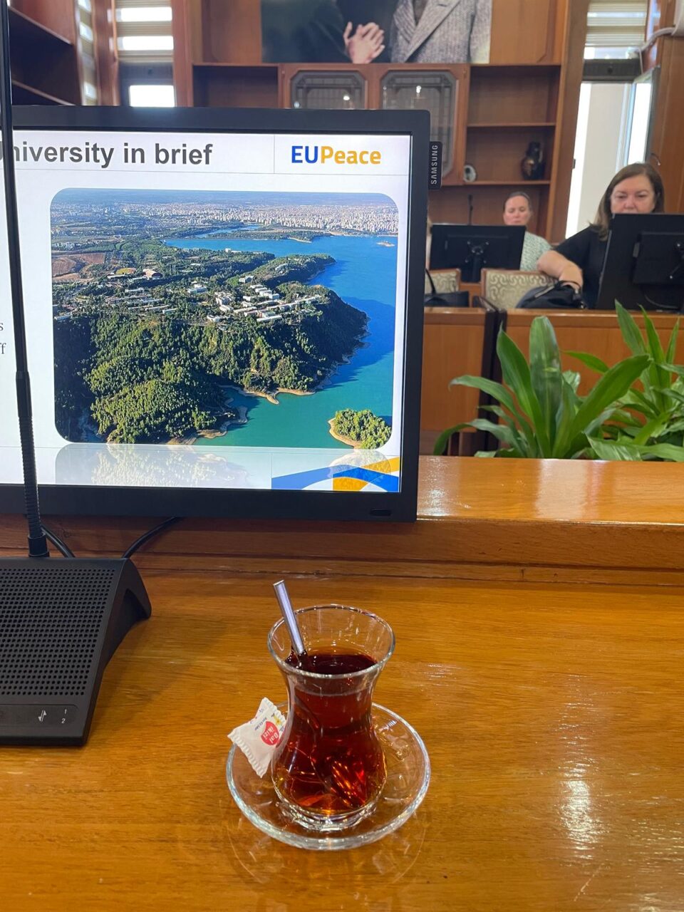 A glass with some brown in front of a computer screen.