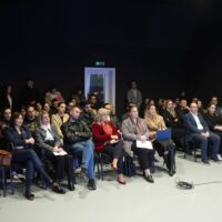 Group of people sitting on chairs and listening to a presentation.