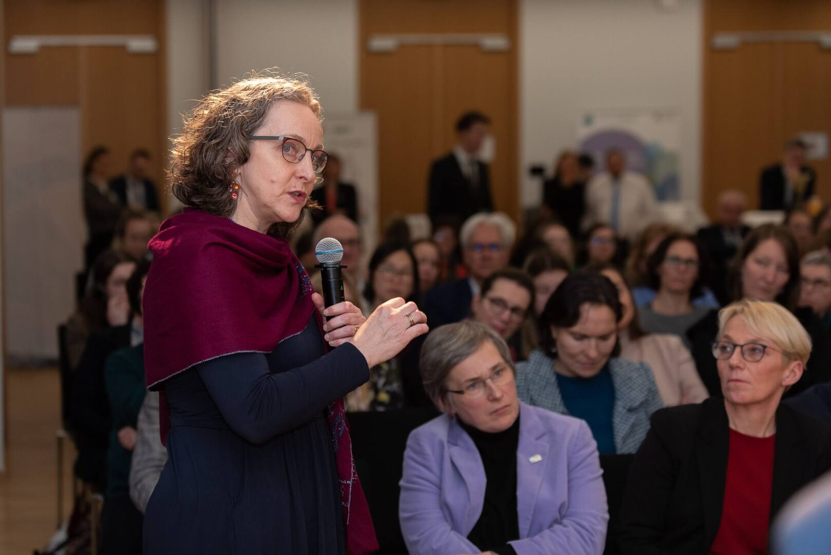 Prof. Dr. Evelyn Korn speaking during a panel session, with the audience visible at the Brussels lunch debate.