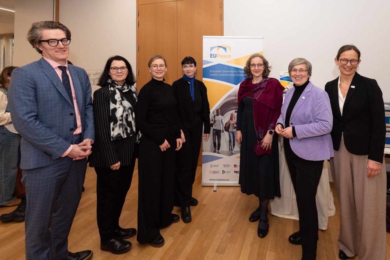 Members of the EUPeace delegation standing in front of an EUPeace roll-up at the Brussels lunch debate.