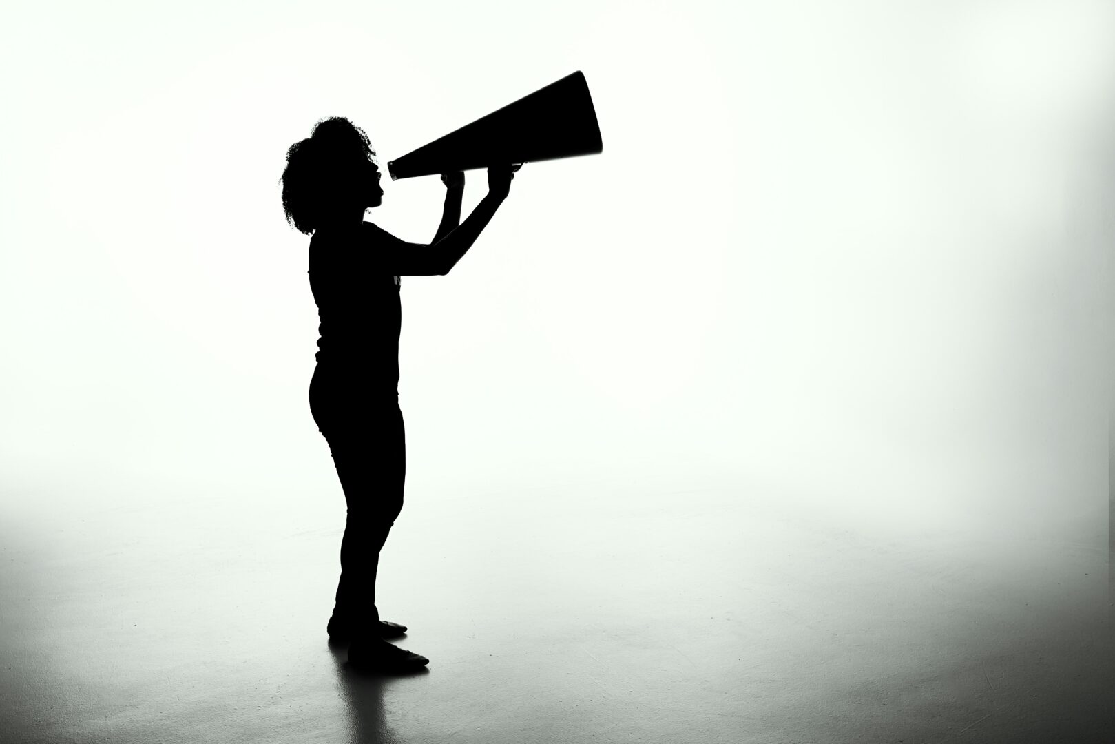 A women in a black shadowy silouette shouting in a megaphone.