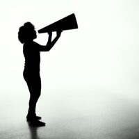 A women in a black shadowy silouette shouting in a megaphone.