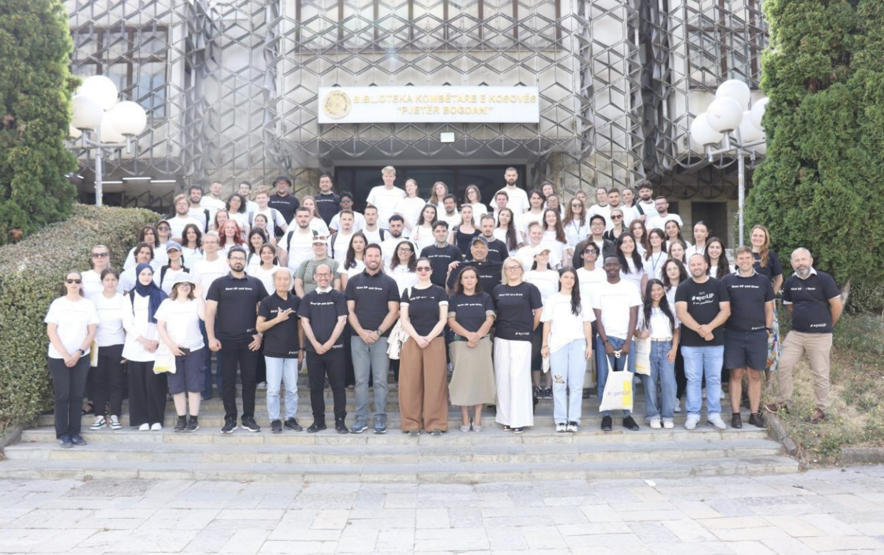 A large group of people standing in front of a building of the University of Prishtina. The group is the organising team of the Prishtina Summer School.