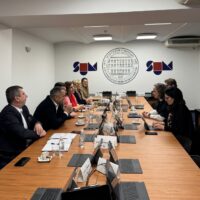 Representatives of Marburg University and the University of Mostar during a meeting at the University of Mostar. The logo of the University of Mostar is visible in the background.