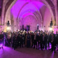 A group of people posing for a picture in an old building with an arched ceiling and purple lighting.