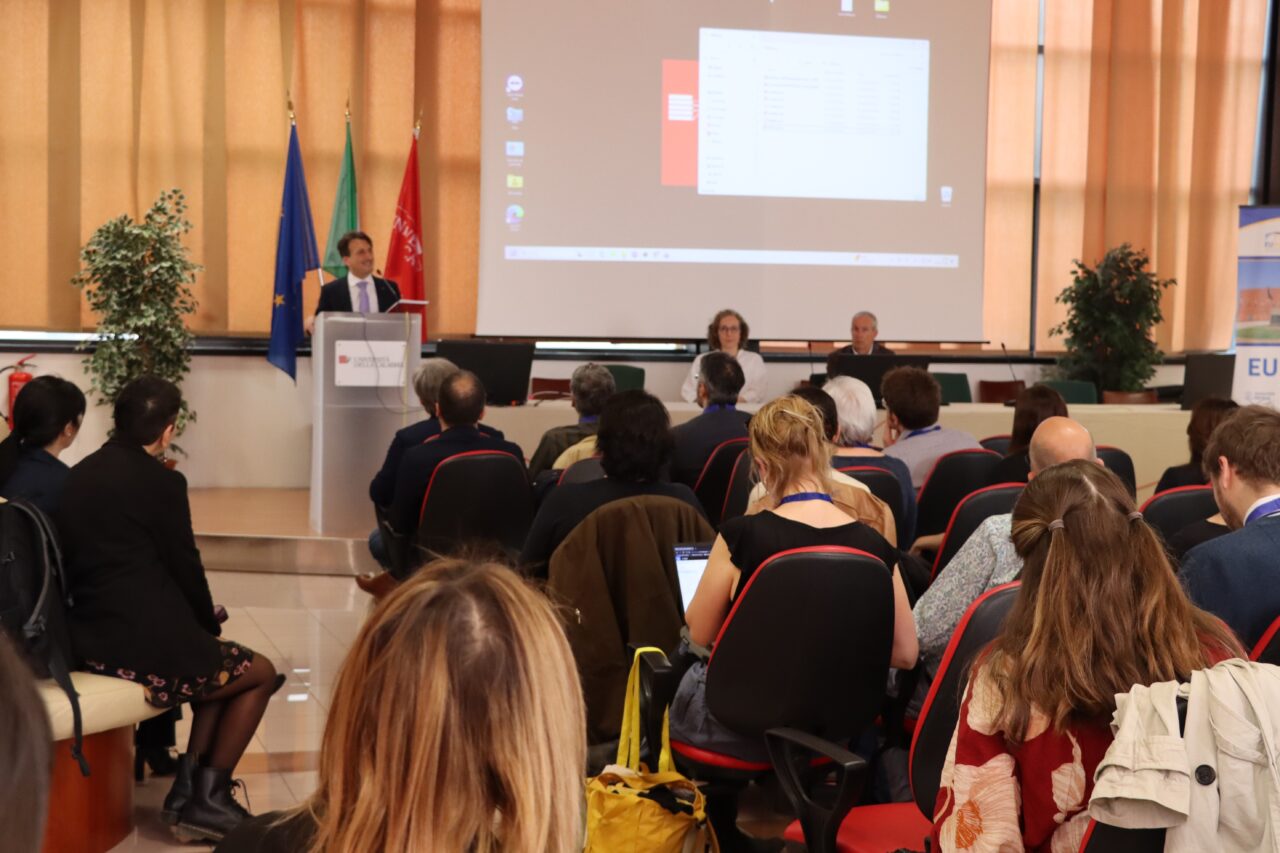 A man holding a presentation in front of an audience. The man is Gianluigi Greco.