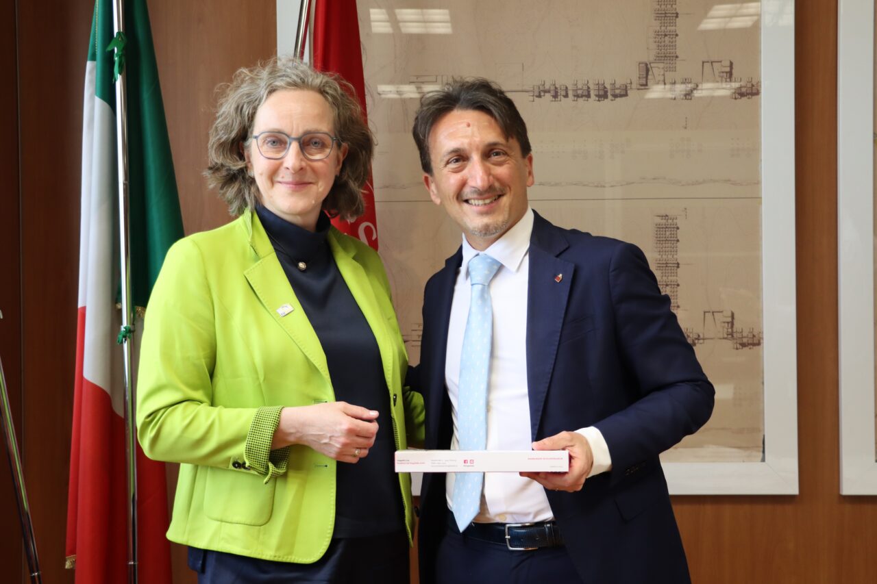 Two persons, a woman and a man, posing for a picture. The man on the right is holding a box of chocolates.