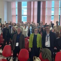 A group of people standing behind their chairs, posing for a picture.