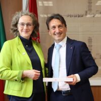 Two persons, a woman and a man, posing for a picture. The man on the right is holding a box of chocolates.