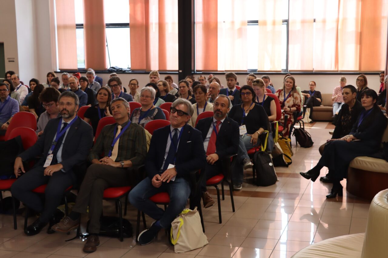 A group of people sitting on chairs, listening to someone out of frame.