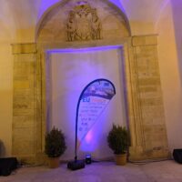 An EUPeace dropflag in front of a wall with arched ceilings, illuminated by blue lighting.