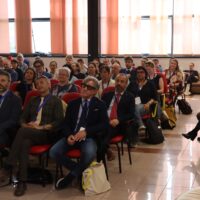 A group of people sitting on chairs, listening to someone out of frame.