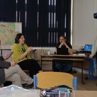 A participant tries on a virtual reality headset during a practical session at a primary school in Pilsen, while other EUPeace BIP participants observe and discuss nearby.