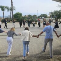 A large group of people participating in a shrinking circle activity in Tropea, Italy.