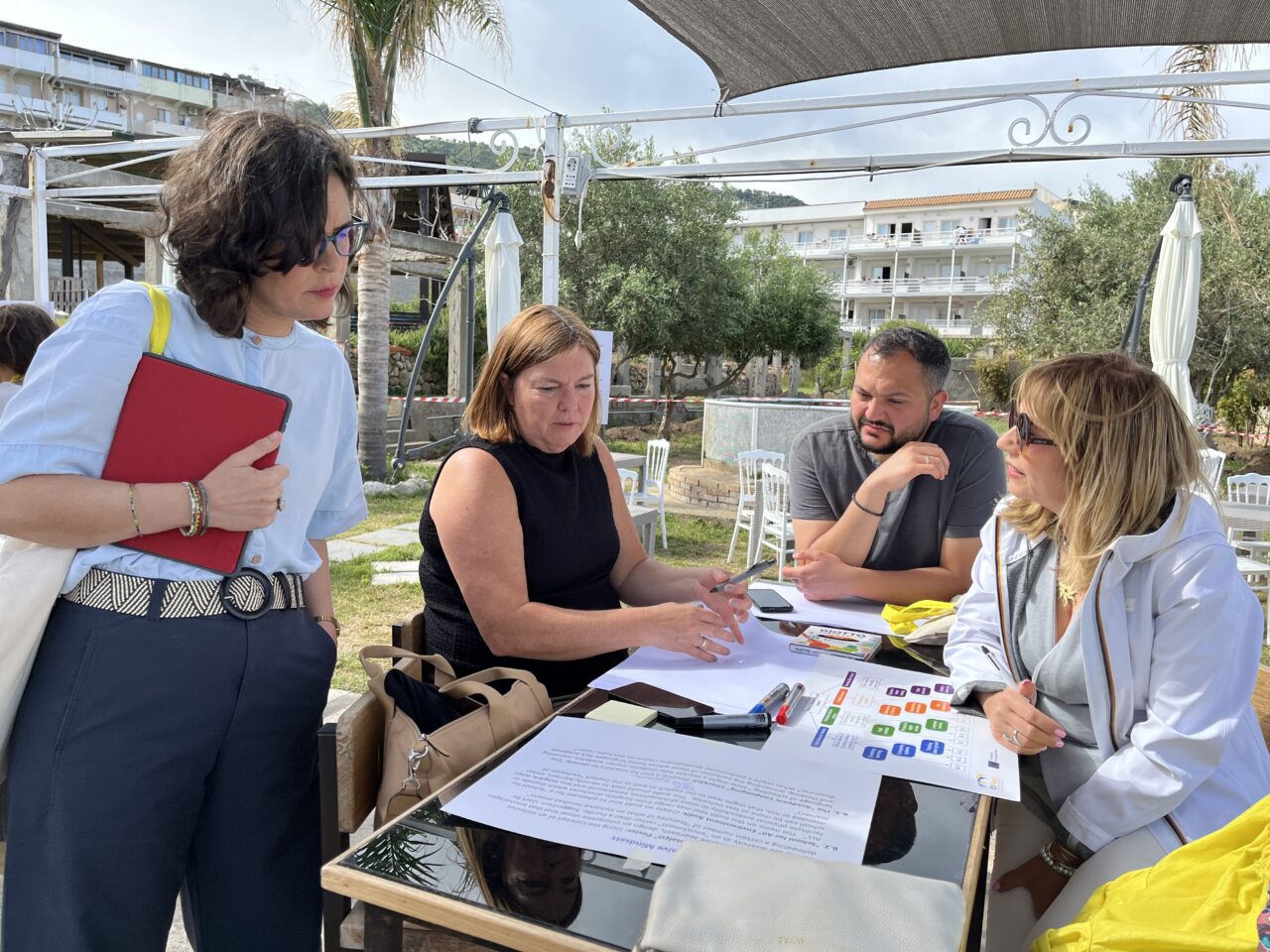 A group of four participants discussing the documents laying on the table in Tropea, Italy.