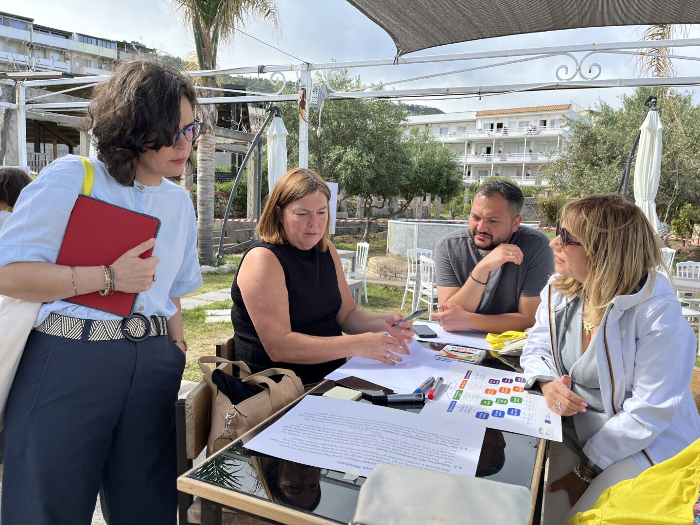 A group of four participants discussing the documents laying on the table in Tropea, Italy.