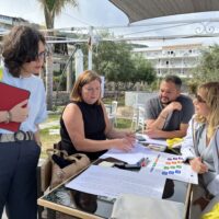 A group of four participants discussing the documents laying on the table in Tropea, Italy.