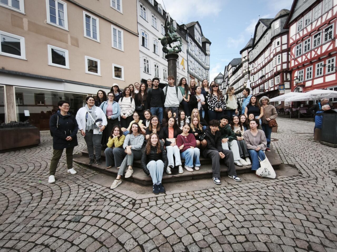 A group of pre-service teachers and colleagues from the University of Limoges, posing for a group photo in front of a fountain in the Old Town of Marburg, Germany.