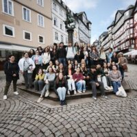 A group of pre-service teachers and colleagues from the University of Limoges, posing for a group photo in front of a fountain in the Old Town of Marburg, Germany.