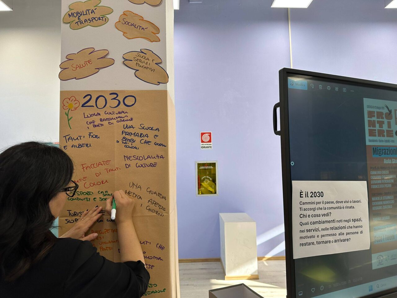 A person writing on a poster hanging on a pillar with "2030" written on the top.