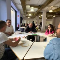 Participants attending the EUPeace Bridge Dialogue and Living Lab session at the University of Calabria during the Frontiere Festival. They are sitting in the groups around tables and conversating.