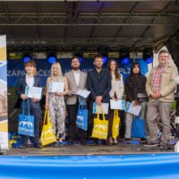A group of students and staff standing on a stage next to an EUPeace banner, holding their European Track Certificates and EUPeace tote bag.