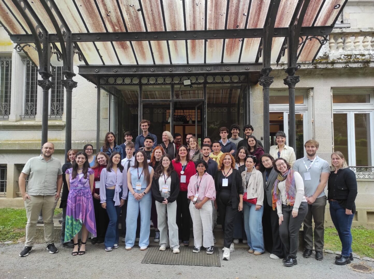 A group of students and staff standing in front of a building's entrance, posing for a group photo.