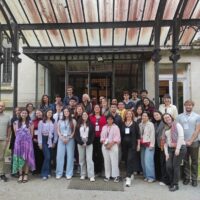 A group of students and staff standing in front of a building's entrance, posing for a group photo.