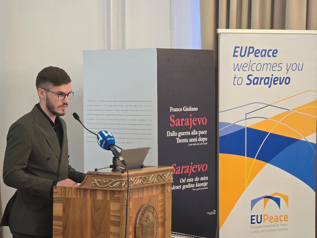 A person standing behind a podium, speaking into the microphone. The person is Imran Pašalić.