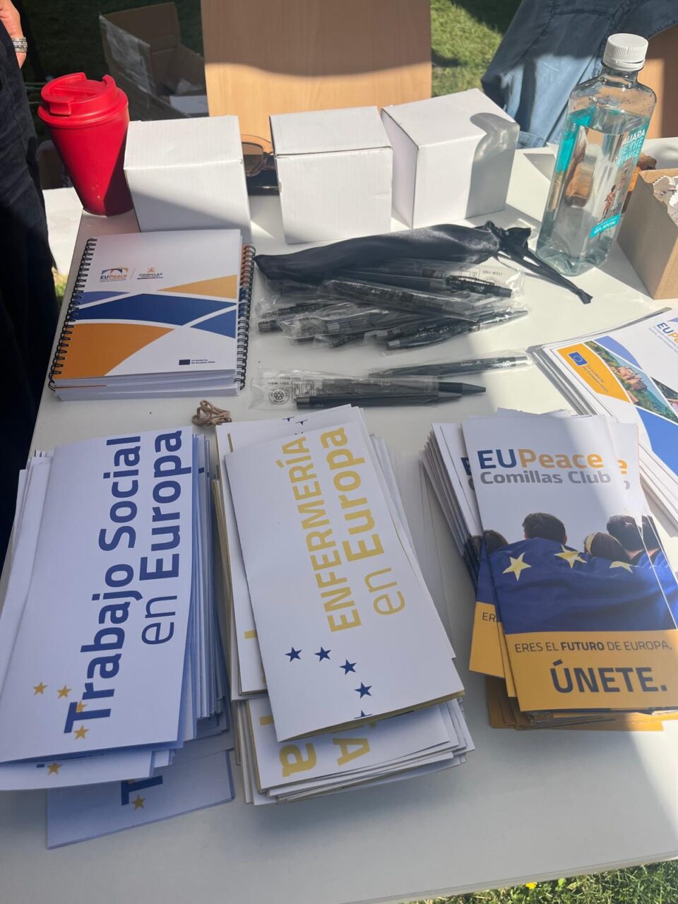 The EUPeace information stand displays brochures, notebooks, pens, and materials for new students.