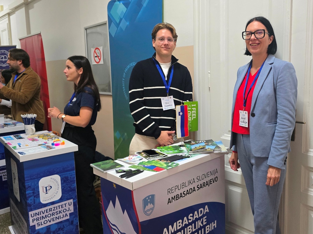 Representatives of the Embassy of Slovenia and the University of Primorska stand at their exhibition tables.