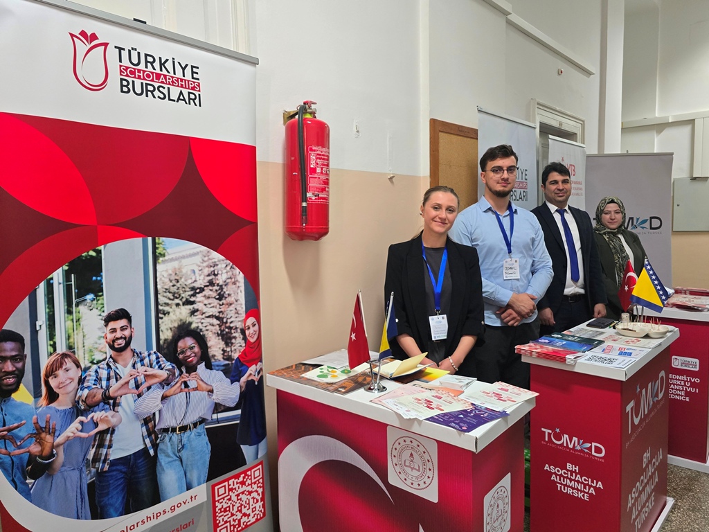 Four representatives stand behind the Türkiye Scholarships and Turkish alumni association tables with Turkish and Bosnian flags.