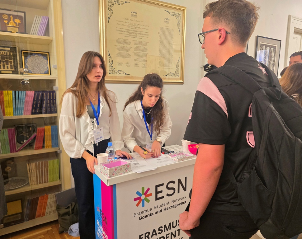 Two young women at the Erasmus Student Network Bosnia and Herzegovina stand speak with a student wearing a backpack.