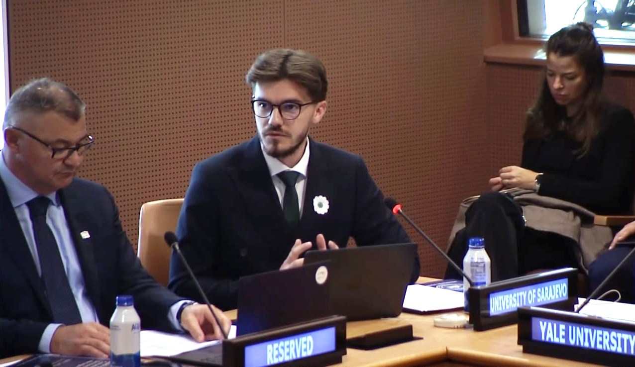 Imran Pašalić speaks into a microphone beside the University of Sarajevo nameplate.