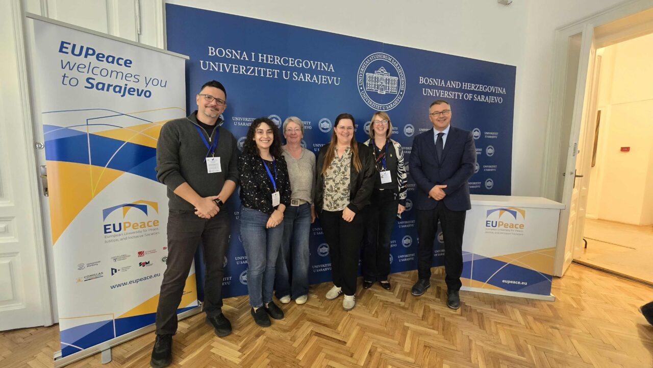 Six EUPeace representatives pose for a group photo in front of University of Sarajevo signage and an EUPeace welcome banner.