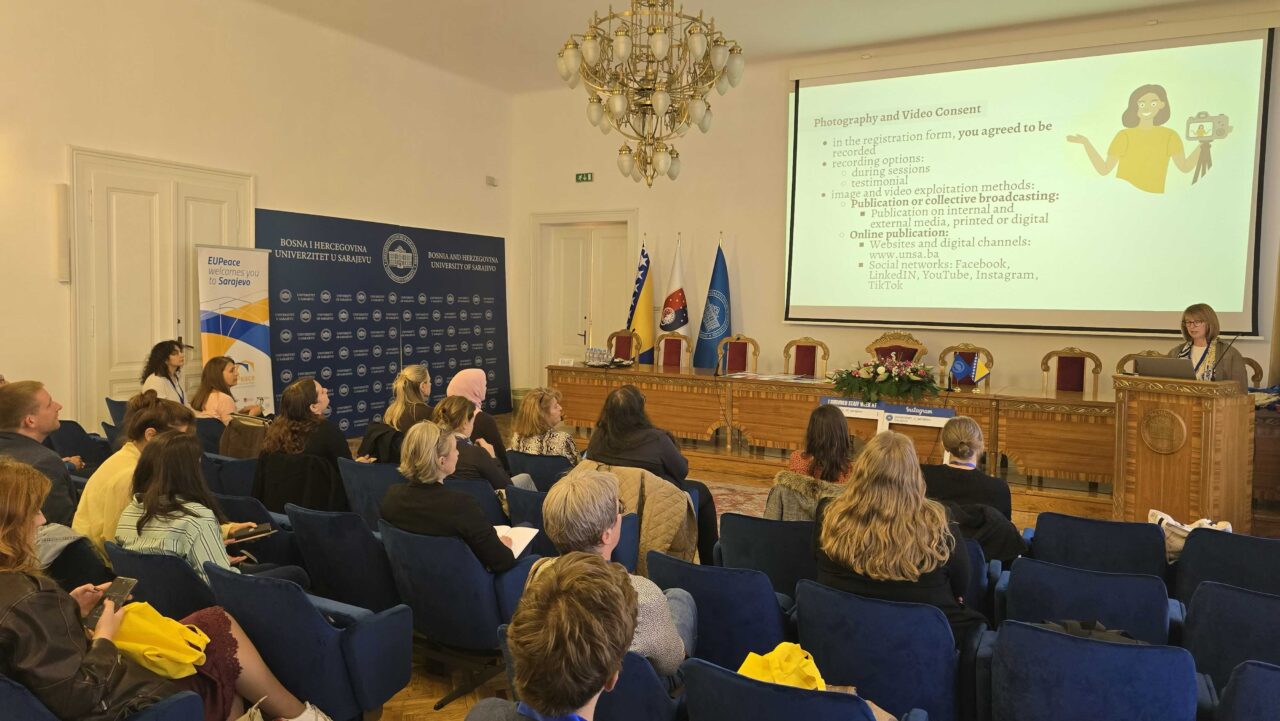 Participants attend a presentation in a university auditorium, where a speaker discusses photography and video consent at the University of Sarajevo.