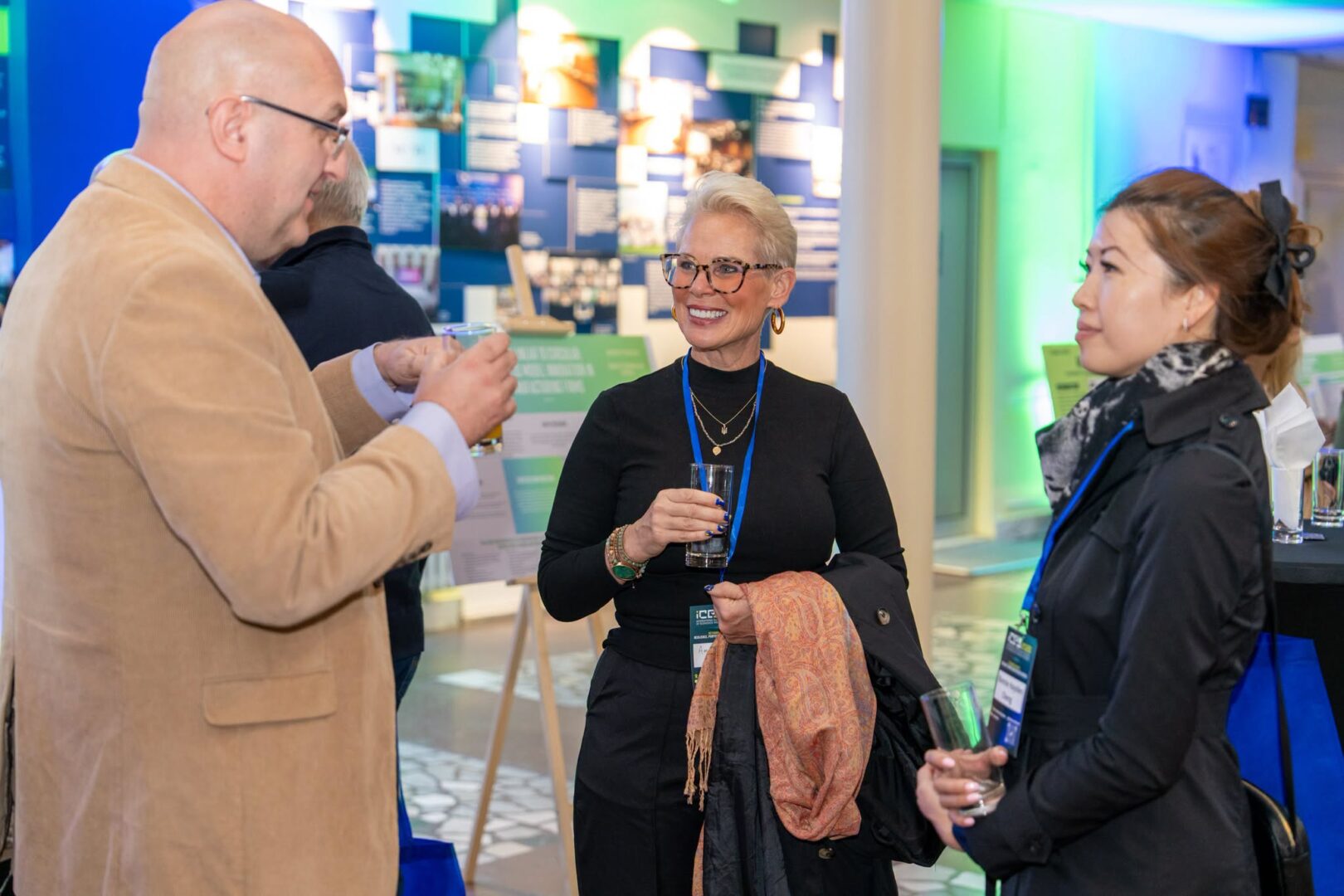 Three conference participants converse over refreshments beside research displays at ICES 2026.