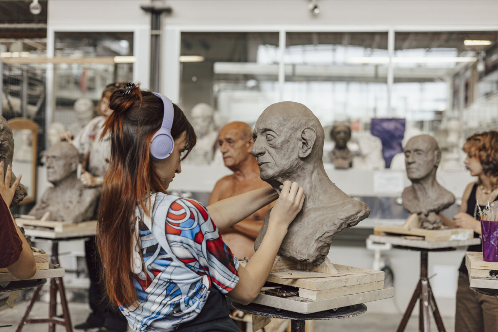 Participants at ArtCamp sculpt life‑size clay head studies during a clay modelling course.