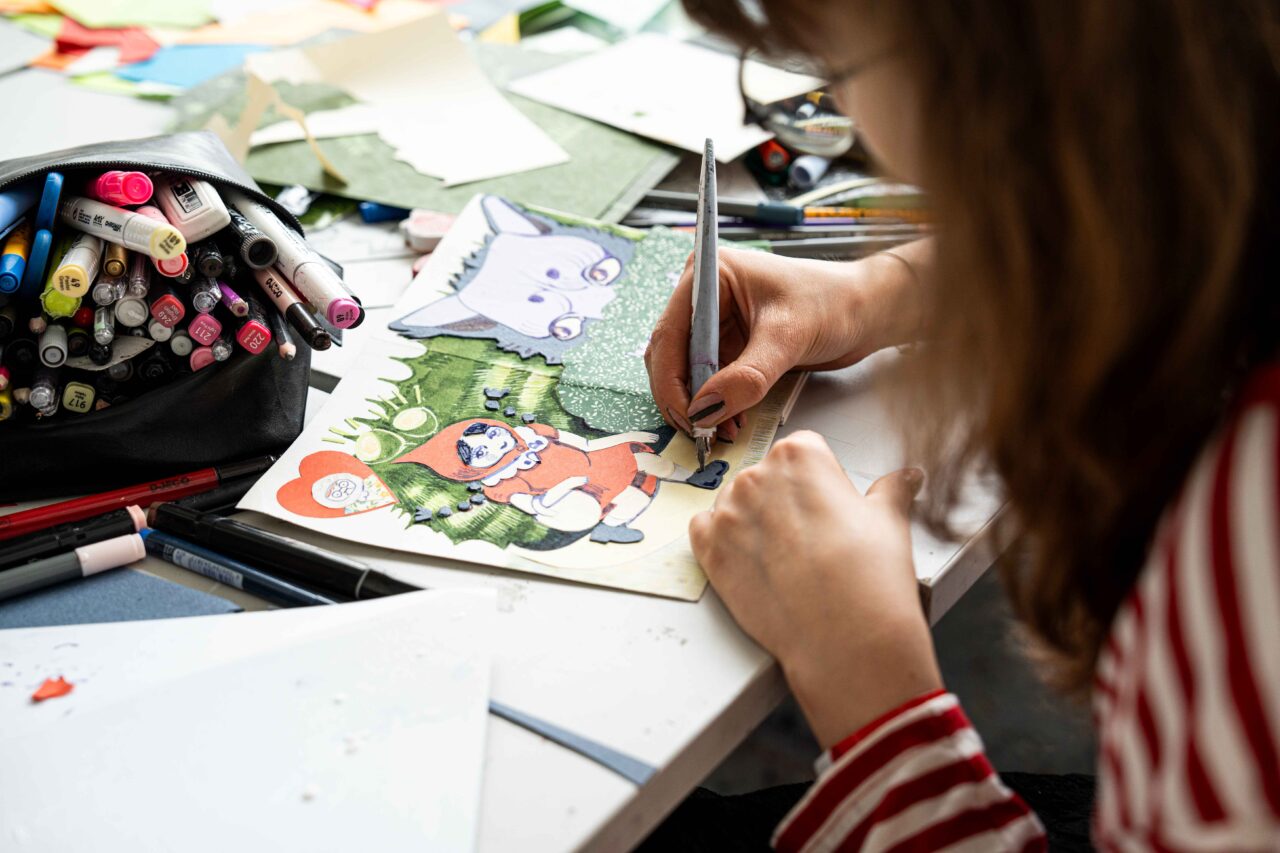 Participant at ArtCamp creating a mixed media illustration inspired by Little Red Riding Hood.