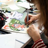 Participant at ArtCamp creating a mixed media illustration inspired by Little Red Riding Hood.