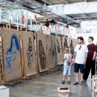 Visitors viewing participants’ artworks at an open exhibition at ArtCamp summer school.
