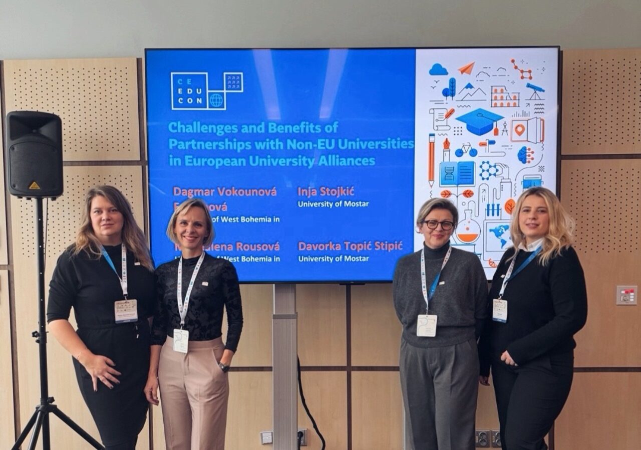 Four women posing in front of a screen for a group picture. The screen shows the logo of the CEEDUCON Conference, the topic of the workshop, and the moderators' names and universities.